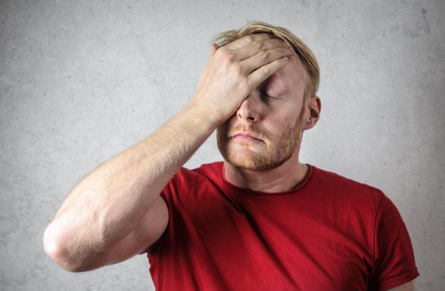 a man in red shirt covering his face