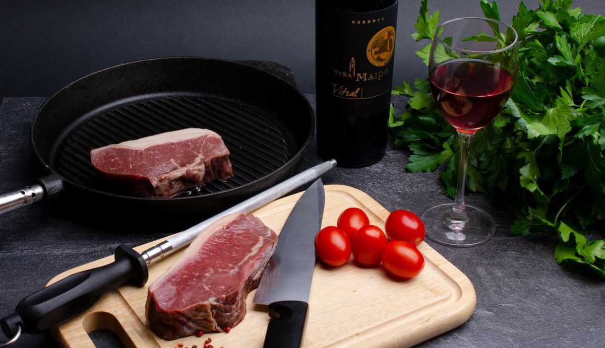 raw meat steaks with parsley tomato and wine